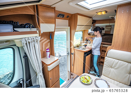 Woman cooking in camper, motorhome interior 65765328