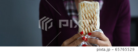 Girl holds delicious shawarma snack during work. Girl holds delicious shawarma snack during work. 65765529