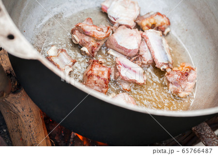 Pieces of lamb meat on bones stew in a cauldron 65766487