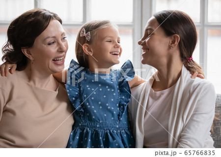 Smiling three generations of women relax on couch together 65766835