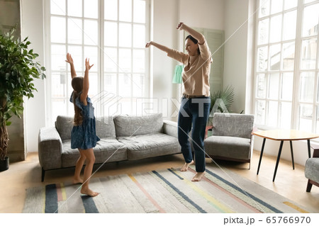 Energetic grandmother dancing in living room with granddaughter 65766970