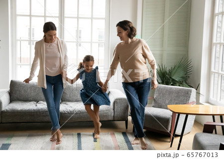 Energetic three generations of women dancing at home 65767013