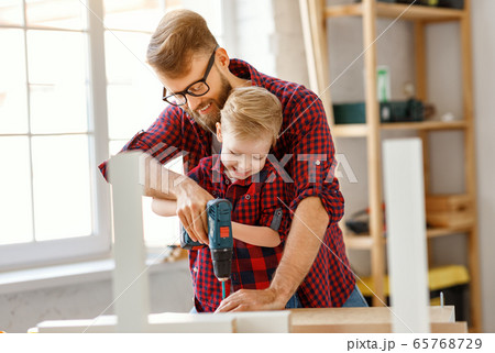 Happy kid helping father in carpentry studio. Happy kid helping father in carpentry studio. 65768729