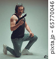 Action hero muscled man holding a gun,Studio shot 65770046