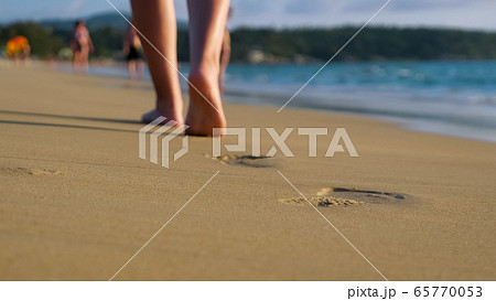 barefoot lady walks along empty ocean beach under blue sky barefoot lady walks along empty ocean beach under blue sky 65770053