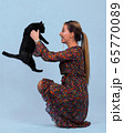 pretty young girl holds a black cat in her arms 65770089