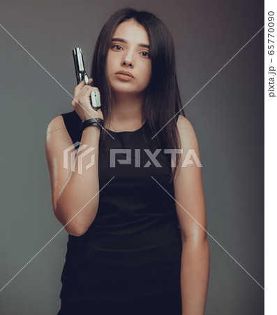 Shot of a sexy military woman posing with guns Shot of a sexy military woman posing with guns 65770090