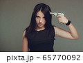 Young woman at despair holding a gun to her head 65770092