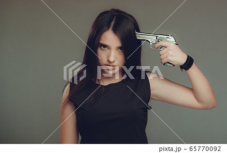 Young woman at despair holding a gun to her head Young woman at despair holding a gun to her head 65770092