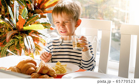 Portrait of little toddler boy refuses drinking juice during breakfast in dining room 65770523