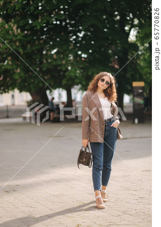 Portrait of attractive woman with curly hair in sunglasses outdoors. Happy young woman walking in the city Portrait of attractive woman with curly hair in sunglasses outdoors. Happy young woman walking in the city 65770826