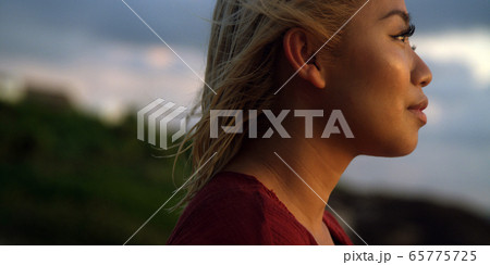 Profile of young woman takes in a sunset while on vacation  65775725