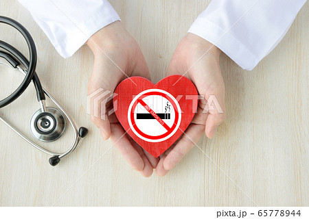 禁煙ステッカーを貼ったハートのオブジェをもつ医師 65778944