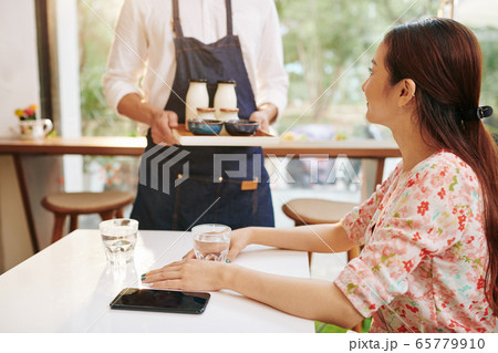 Cafe customer having her breakfast served Cafe customer having her breakfast served 65779910