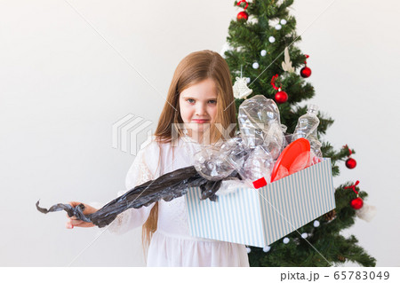 Environmental protection and pollution concept. Sad child carrier box with plastic trash over christmas tree background. Environmental protection and pollution concept. Sad child carrier box with plastic trash over christmas tree background. 65783049