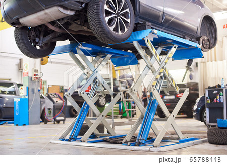 Automobile raised on lift for repairing in auto repair shop. 65788443