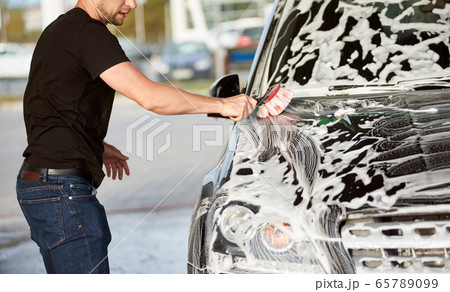 Sporty man washing his black car outdoors Sporty man washing his black car outdoors 65789099
