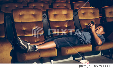A boy laying down and playing mobile phone 65794331