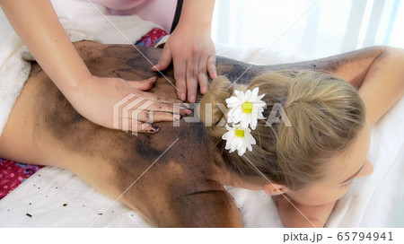 Relaxed woman lying on spa bed for body scrubbing. Relaxed woman lying on spa bed for body scrubbing. 65794941
