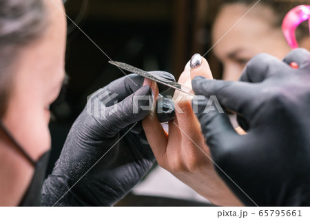 Close-up of hardware milling cutter for removing gel polish. Apparatus manicure in beauty salon. Manicurist with electric nail drill remove old gel from client nails. Process of replacing old shellac. 65795661