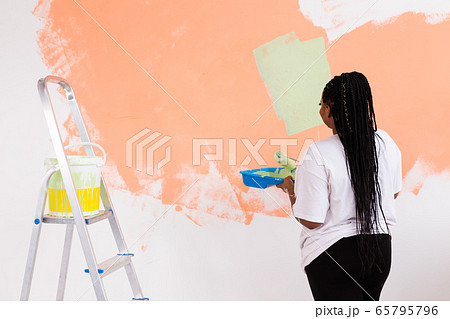 Afro american woman painting an apartment. Renovation, repair and redecoration concept. 65795796