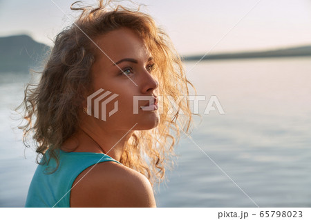 Portrait of serious pretty girl on background of lake. 65798023