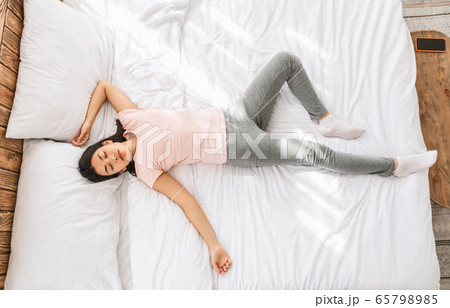 Asian Woman Sleeping In Funny Pose Lying In Bed, Top-View 65798985