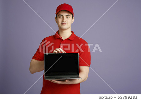 Order courier at home online. Deliveryman holding laptop with blank screen Order courier at home online. Deliveryman holding laptop with blank screen 65799283