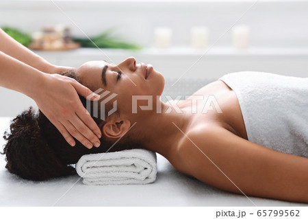 Young black woman getting head massage from massage therapist Young black woman getting head massage from massage therapist 65799562