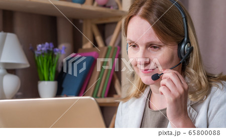 The woman communicates with customers from home, speaks in the headset. Home office 65800088