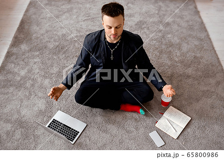 Reflective man with laptop sit in lotus on carper  65800986