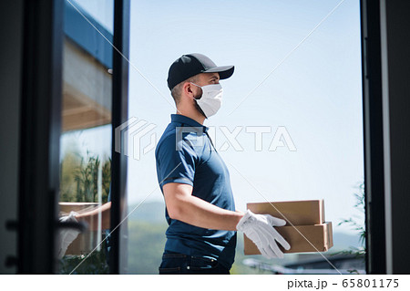 Courier with face mask delivering parcel, corona virus and quarantine concept. Courier with face mask delivering parcel, corona virus and quarantine concept. 65801175