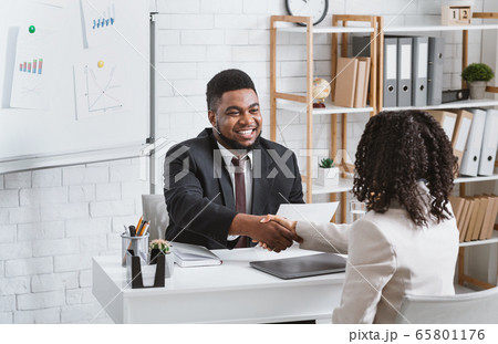 Personnel manager and young job applicant shaking hands at modern company office Personnel manager and young job applicant shaking hands at modern company office 65801176