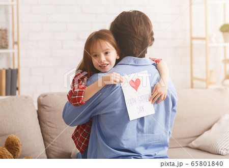 Cute little girl hugging dad, holding greeting card 65801840