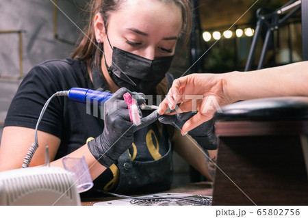 Close-up of hardware milling cutter for removing gel polish. Apparatus manicure in beauty salon. Manicurist with electric nail drill remove old gel from client nails. Process of replacing old shellac. 65802756