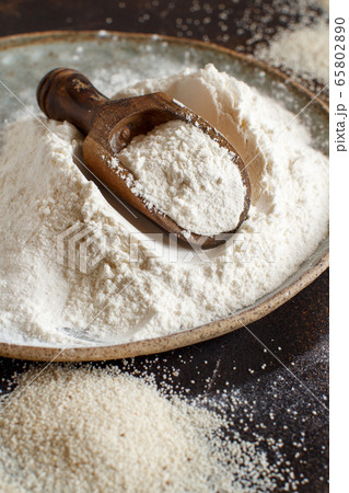 Raw fonio flour and seeds with a spoon on dark 65802890