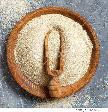 Raw uncooked fonio seeds with a spoon on a plate 65802896