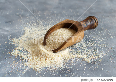 Raw uncooked fonio seeds with a spoon on grey 65802899