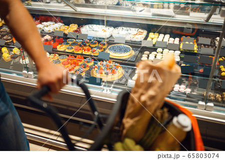 Man at the showcase with cakes in grocery store 65803074