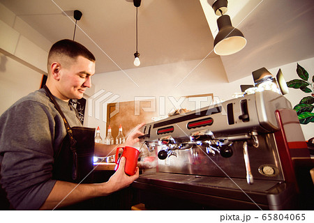 Barista preparing coffee in a coffee shop. Professional coffee making, service and catering concept Barista preparing coffee in a coffee shop. Professional coffee making, service and catering concept 65804065