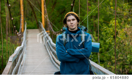 Young man traveler standing on the bridge and looking in the camera 65804880