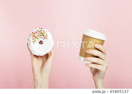 Woman hand holds paper cup with coffee and donut Woman hand holds paper cup with coffee and donut 65805137