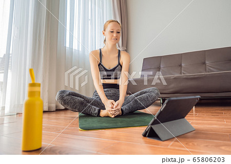 Fitness woman exercising on the floor at home and watching fitness videos in a tablet. People do Fitness woman exercising on the floor at home and watching fitness videos in a tablet. People do 65806203