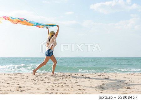 Summer Vacation. Lifestyle woman running and holding scarf Summer Vacation. Lifestyle woman running and holding scarf 65808457