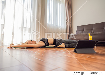 Fitness woman exercising on the floor at home and watching fitness videos in a tablet. People do 65808462