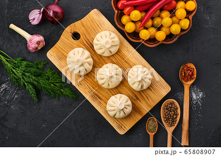 Top view of uncooked khinkali on wooden board with spice and herbs 65808907