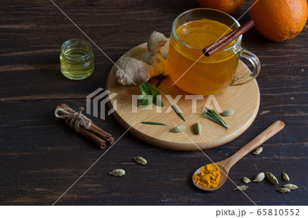 Ginger tea with saffron in a glass Cup and ingredients on a dark wooden table Ginger tea with saffron in a glass Cup and ingredients on a dark wooden table 65810552