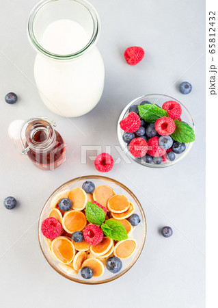 Tiny cereal pancakes served with maple syrup 65812432