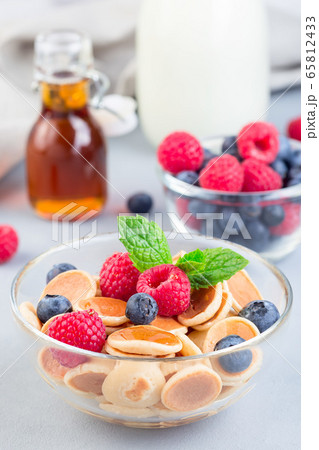 Tiny cereal pancakes served with maple syrup 65812433