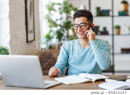 Cheerful ethnic freelancer answering phone call Cheerful ethnic freelancer answering phone call 65813147